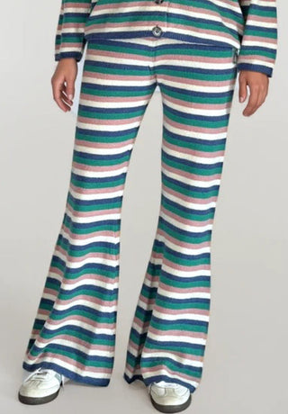 Woman wearing pink, white, blue and green striped, flared sweater pants.White/grey background.