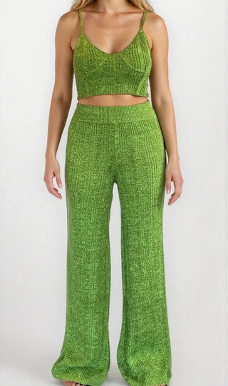 Woman wearing green knit crop tank and matching flare bottoms. White/grey background.