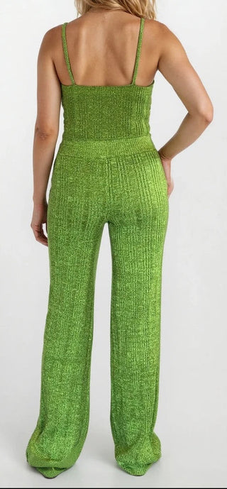 Back view of a woman wearing green knit crop tank and matching flare bottoms. Grey/white background.