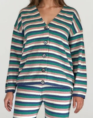 Woman wearing a white, pink, blue, green stripe button up cardigan. White/grey background.